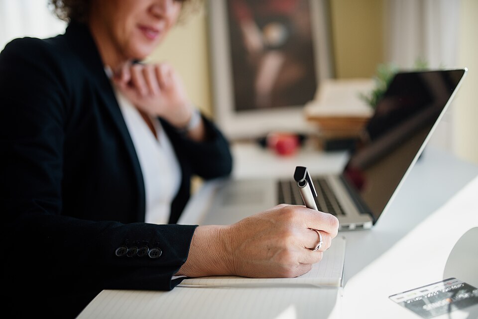 Business professional engages in note-taking during a meeting at a modern office desk.jpg